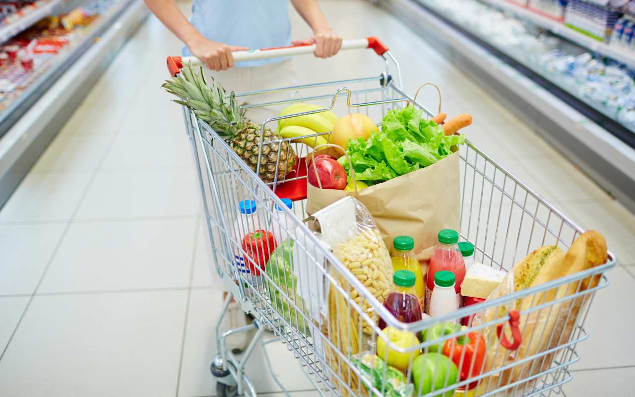 Una persona al supermercato con il carrello della spesa pieno