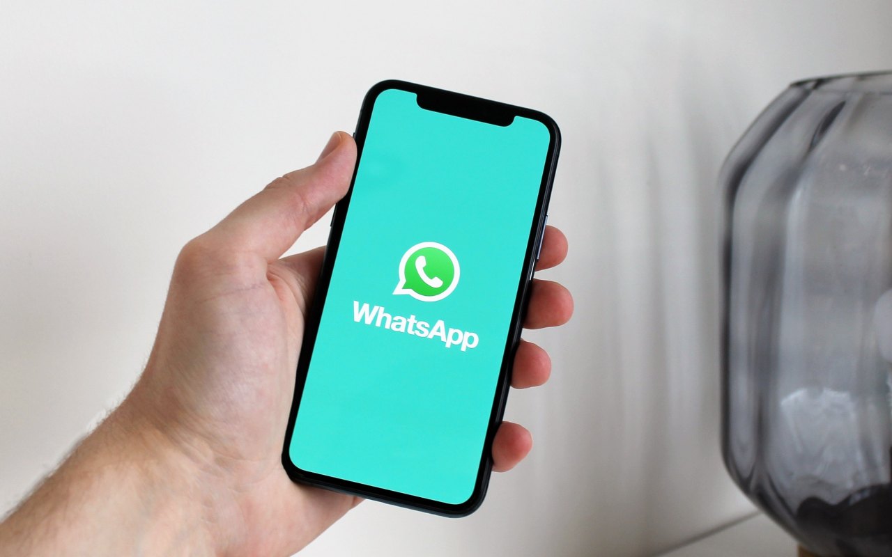 Una persona tiene in mano uno smartphone con l'applicazione di messaggistica WhatsApp sullo schermo