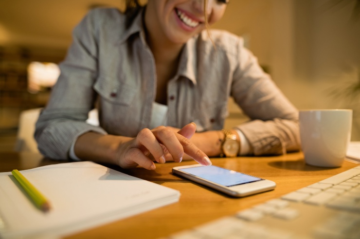 Una ragazza sorride mentre scrive sullo smartphone 