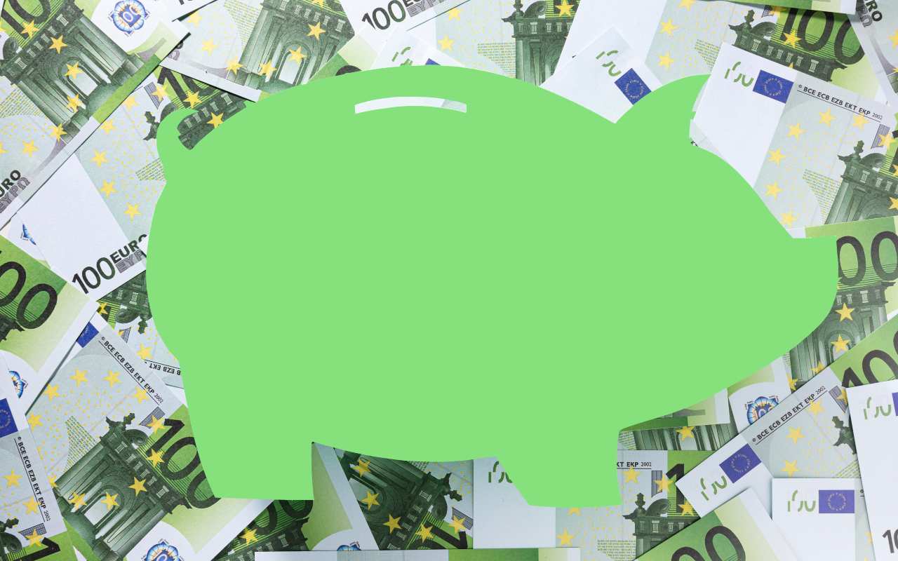 Banconote da 100 euro con un salvadanaio verde in primo piano