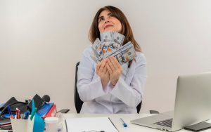 Una donna tiene in mano delle banconote seduta alla scrivania di lavoro